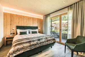 a bedroom with a bed and a chair and a window at Amie Chalet in Santa Cristina in Val Gardena