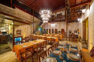 a restaurant with wooden tables and chairs and a chandelier at Le Reve Butik Otel in Hatay