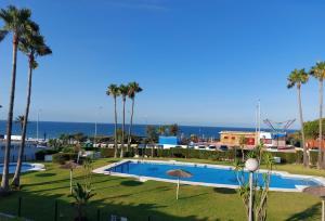 duży basen z palmami i oceanem w obiekcie Precioso apartamento en primera línea de playa de la Barrosa w mieście Chiclana de la Frontera +3 zdjęcia