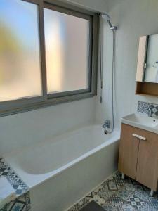 bagno con vasca, lavandino e finestra di leflamantduport a Hyères