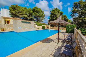 una piscina con sillas y sombrilla en Magdalena - holiday bungalow with pool in Teulada, en Teulada