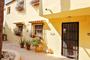 un edificio amarillo con dos ventanas y macetas en Magdalena - holiday bungalow with pool in Teulada, en Teulada 16 fotos más