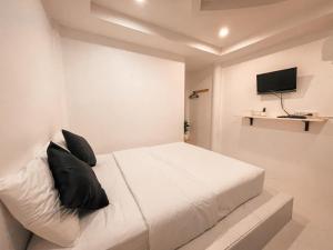 um quarto com uma cama branca e almofadas pretas em KohLan Hansa em Ko Larn