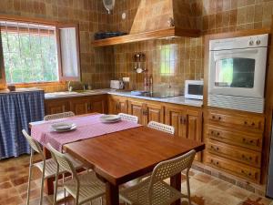 a kitchen with a wooden table with chairs and a microwave at CAN MARIANO BARBER in La Mola