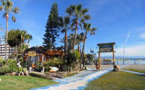 une passerelle à côté d'une plage bordée de palmiers dans l'établissement DIAMOND TORREMOLINOS TROPICAL, à Torremolinos