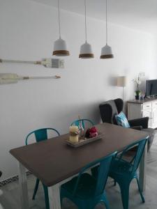 stół jadalny z niebieskimi krzesłami i świetlikami w obiekcie Precioso apartamento en primera línea de playa de la Barrosa w mieście Chiclana de la Frontera