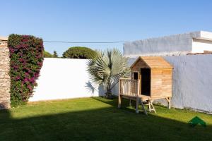 a yard with a wooden chair and a dog house at Villa La Barrosa in Chiclana de la Frontera