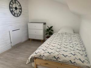 1 dormitorio con 1 cama y reloj en la pared en Appartement Duplex 65m Bordeaux Saint Augustin, en Mérignac