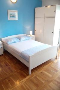 a bedroom with a white bed and a blue wall at Apartments with a parking space Grebastica, Sibenik - 4866 in Grebaštica
