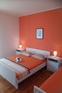 a bedroom with a bed with an orange wall at Apartments with a parking space Grebastica, Sibenik - 4866 in Grebaštica