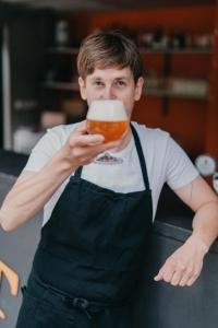 un hombre en delantal bebiendo un vaso de cerveza en Hotel Split en Kadaň