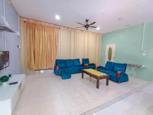 a living room with blue couches and a table at Villa Bonda Langkawi in Pantai Cenang