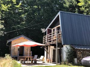 a cabin with an umbrella and a table and chairs at CHARMANT CHALET dans les monts du Forez in Le Fayt