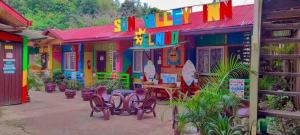 een kleurrijk gebouw met stoelen en tafels ervoor bij Sun Valley Hostel in El Nido