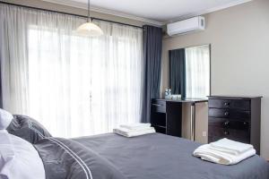 a bedroom with a bed and a dresser and a window at Inviting 3-Bed Apartment In The City in Umtali