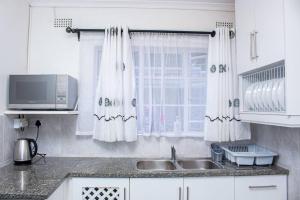 a white kitchen with a sink and a window at Inviting 3-Bed Apartment In The City in Umtali