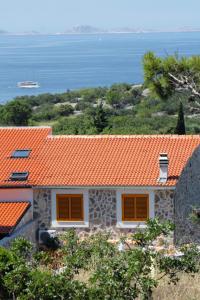 ein Haus mit einem orangenen Dach und dem Meer in der Unterkunft Apartments with a parking space Murter - 5097 in Murter