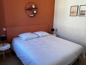 Lostendro, appartements vue port في لو جويلفينيك: غرفة نوم مع سرير أبيض ومرآة على الحائط