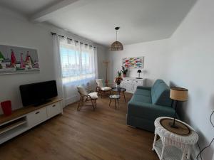 Lostendro, appartements vue port في لو جويلفينيك: غرفة معيشة مع أريكة وتلفزيون
