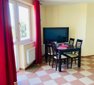 a dining room with a table and chairs and a television at ANNABERG Polanica Zdrój in Polanica-Zdrój