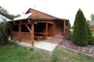 a large wooden building with a porch and a patio at Agroturystyka Nad Tanwią in Budziarze