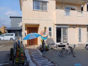 白浜 Mizuki-ya في Kamitondacho: منزل فيه مظلة زرقاء وطاولة وكراسي