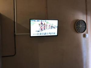 a flat screen tv hanging on a wall with a clock at The Bachelor Private Guest Room in Fernglen