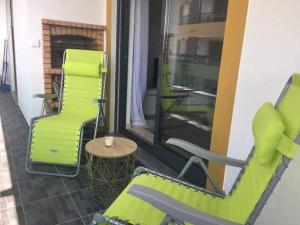 2 grüne Stühle und ein Tisch auf einer Veranda in der Unterkunft Apartamento Cacela- Manta Rota- Altura in Vila Nova De Cacela