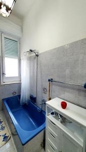 a bathroom with a blue tub and a sink at Casetta Nonna Giacomina 1camera da letto e soggiorno con angolo cottura in Valderice