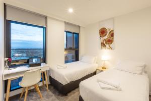 a bedroom with two beds and a desk and a window at Astra Apartments Glen Waverley in Glen Waverley