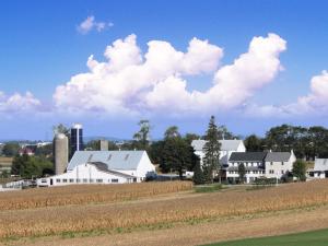 a farm with white buildings and a field and clouds at Amish View Inn & Suites in Bird-in-Hand