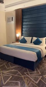 1 dormitorio con 1 cama grande y cabecero azul en فيو إن للشقق الفندقية - المحالة en Abha