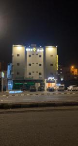 un edificio con coches estacionados en un estacionamiento por la noche en فيو إن للشقق الفندقية - المحالة, en Abha