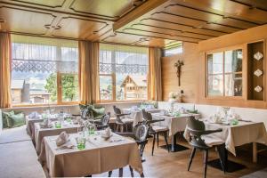 BOUTIQUEHOTEL das edelweiss في شوبرناو: مطعم بطاولات بيضاء وكراسي ونوافذ