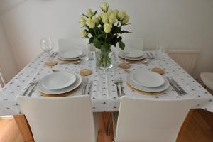a white table with white plates and a vase of flowers at Cosy house, a train spotter's delight! in New Alresford +10 photos