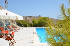 een zwembad met stoelen en een tafel en een parasol bij Archipelagos Boutique Hotel in Skhoinoussa +53 foto's