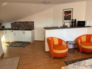 a kitchen with two orange chairs and a counter at Panorama Studio Sighisoara in Sighişoara