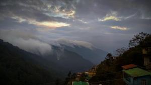uma vista para uma montanha com nuvens no céu em Sunshraya Homestay em Darjeeling