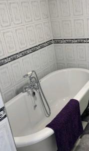 a white bath tub in a bathroom with a purple towel at Beach house in Crosby