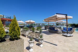 un patio con sillas y sombrillas y una piscina en Villas for 4 or 6 Adults in Therma Village - Private Beach & Free Parking en Kranevo