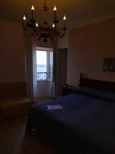 a bedroom with a bed and a chandelier and a window at Belvedere Hotel & Villa in Toscolano Maderno