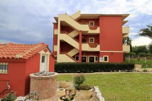 a red and yellow building next to a yard at Lofos ClaudiAgapi Guesthouse Seaview in Agios Stefanos