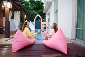 芭達雅中心的住宿－Twenty Two Pool Villa，两名女性坐在带粉红色枕头的庭院