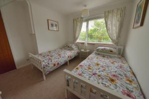 a small bedroom with two beds and a window at Cosy house, a train spotter's delight! in New Alresford