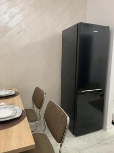 a black refrigerator in a room with tables and chairs at Central Alexa Apartament in Bacău