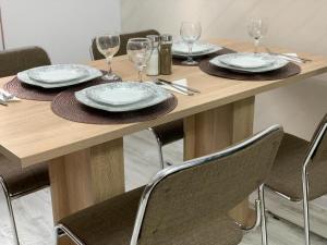 a wooden table with chairs and plates and wine glasses at Central Alexa Apartament in Bacău