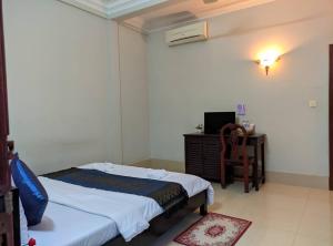 um quarto com uma cama, uma cadeira e uma televisão em IKI IKI Guesthouse em Siem Reap