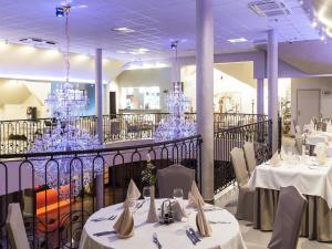a dining room with white tables and chandeliers at Hotel Sevilla in Rawa Mazowiecka