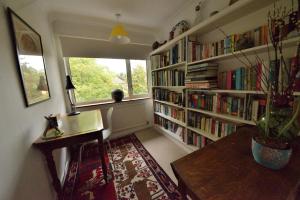 Zimmer mit einer Bibliothek mit einem Schreibtisch und einem Fenster in der Unterkunft Cosy house, a train spotter's delight! in New Alresford