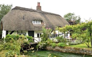 a thatched house with a bridge in front of it at Cosy house, a train spotter's delight! in New Alresford